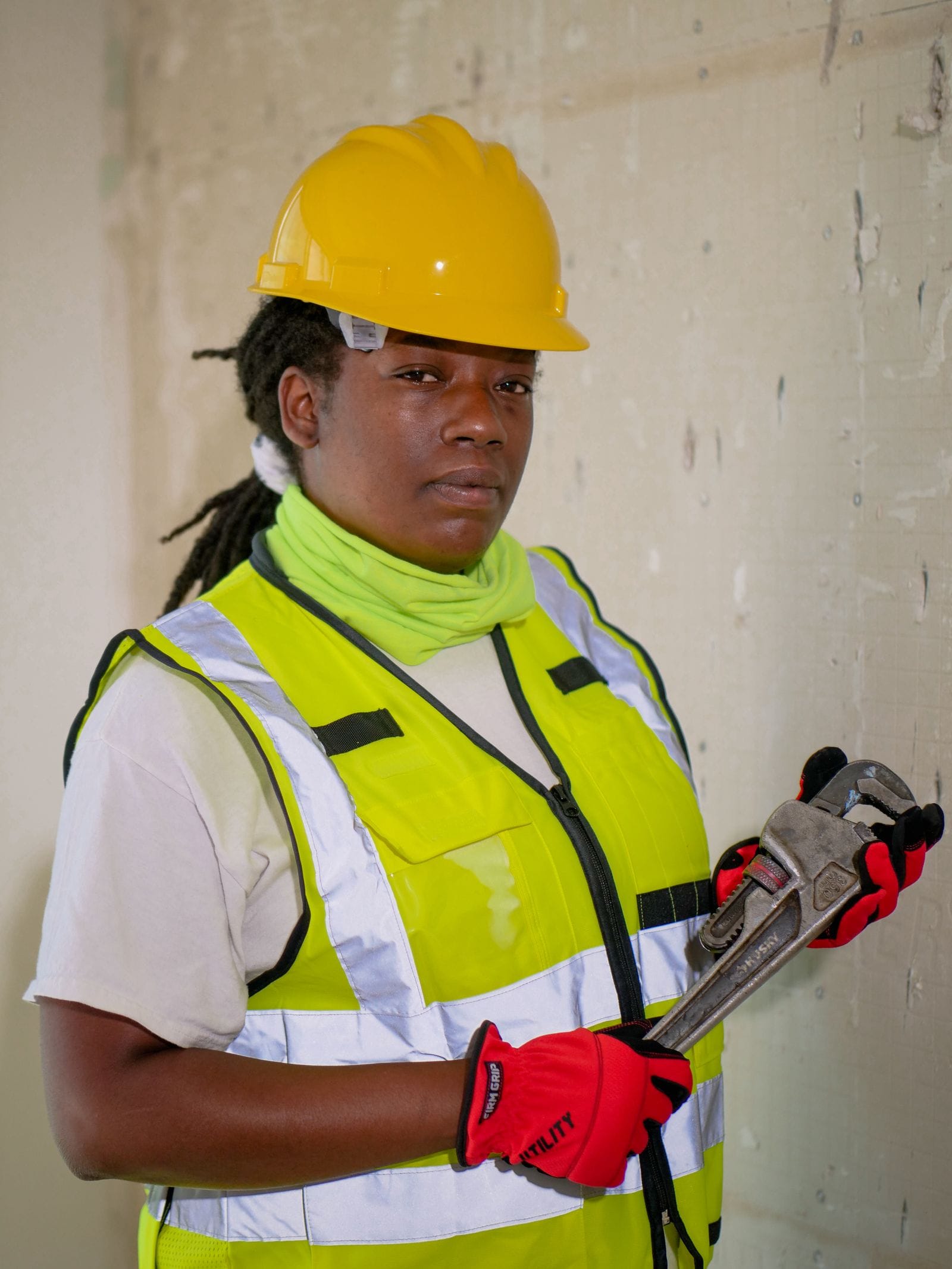 Plumber in safety gear holding a pipe wrench