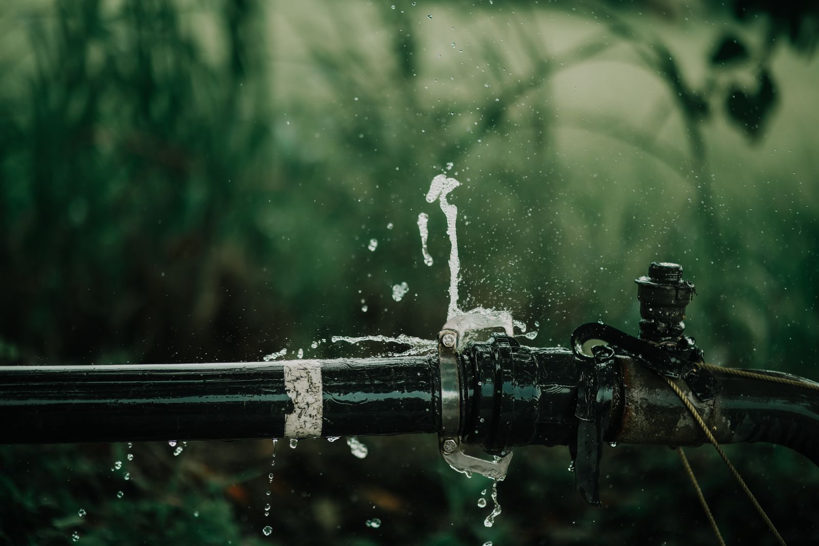 Water spraying from a leaking pipe that needs emergency plumbing repair