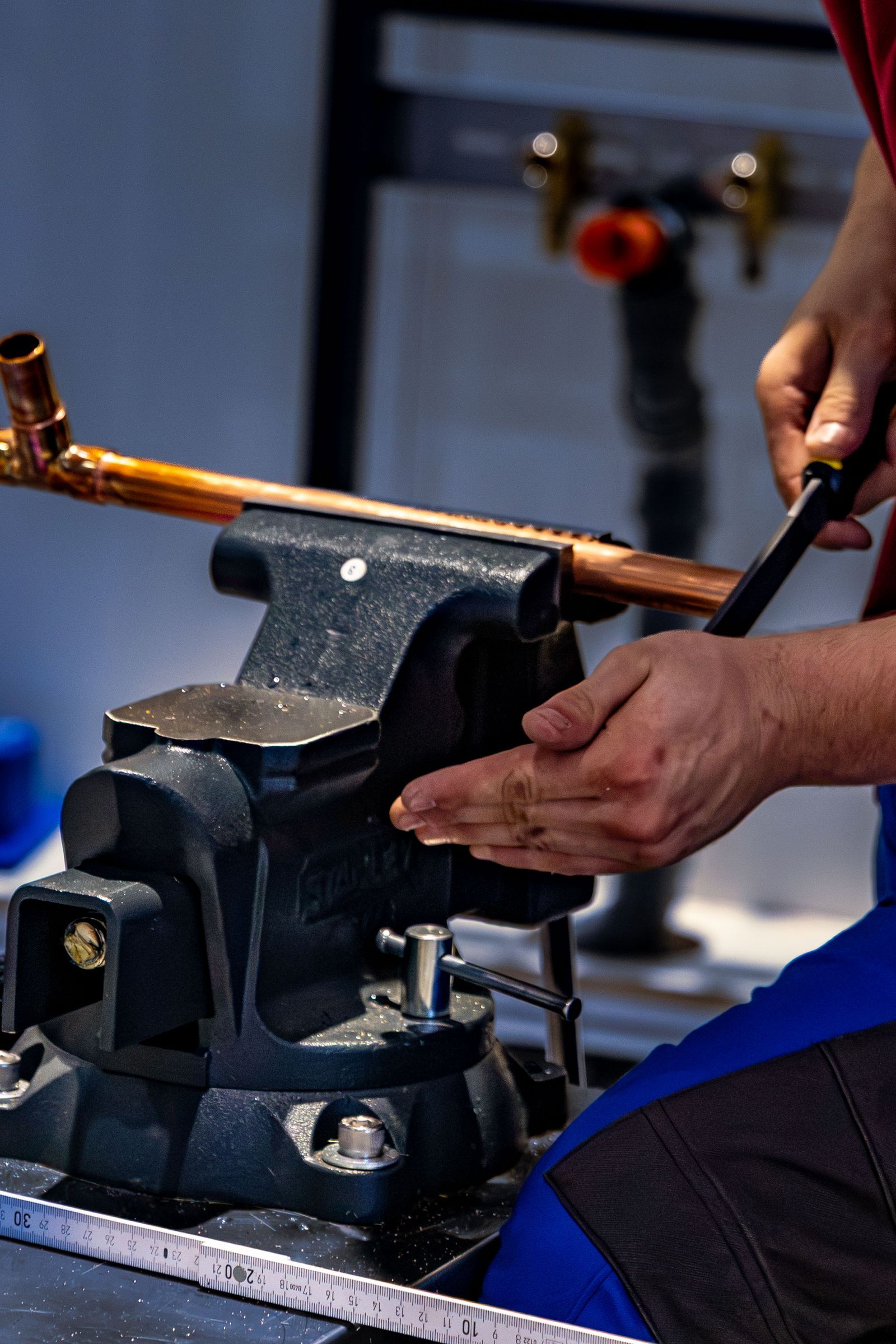 Plumber bending copper pipe in a workshop