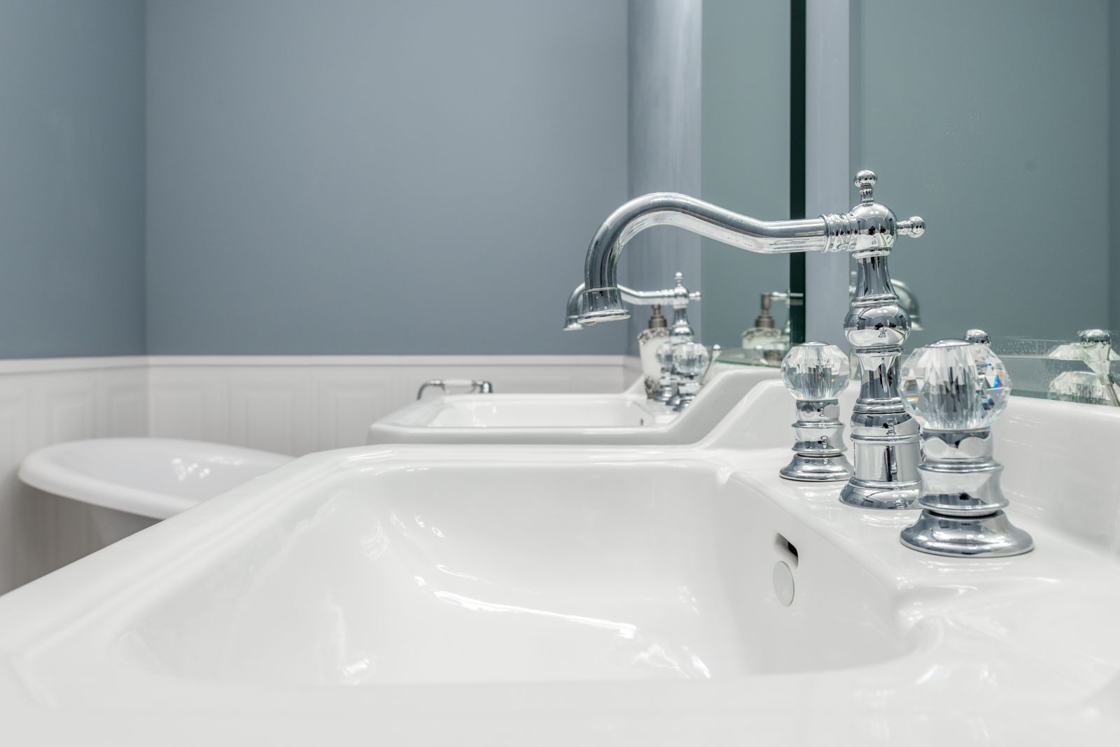 Pair of chrome bathroom sink faucets on a white vanity
